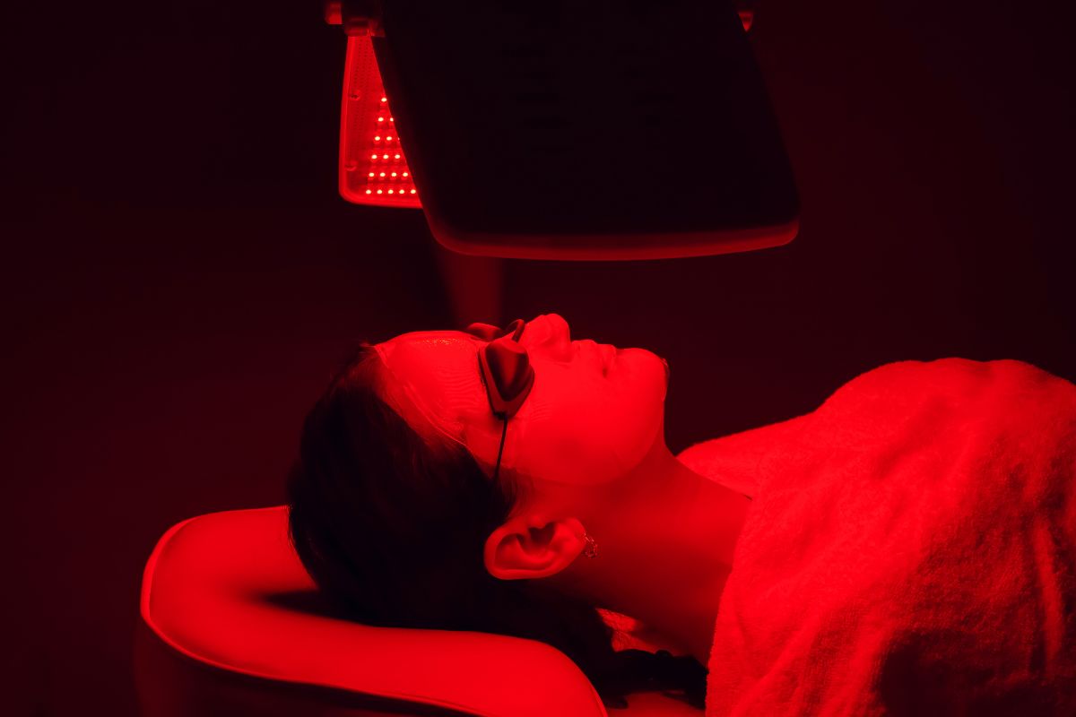 Young woman having red LED light facial therapy